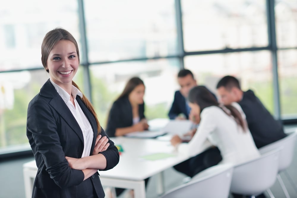 happy young business woman  with her staff,  people group in background at modern bright office indoors